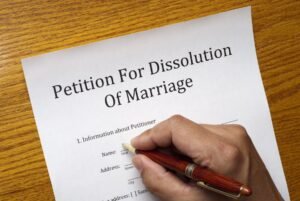 A person is writing on the paper petition for dissolution of marriage.