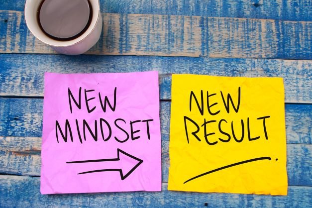 A cup of coffee and two sticky notes with new mindset and new results.