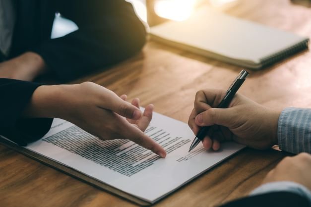 Two people are writing on a piece of paper.