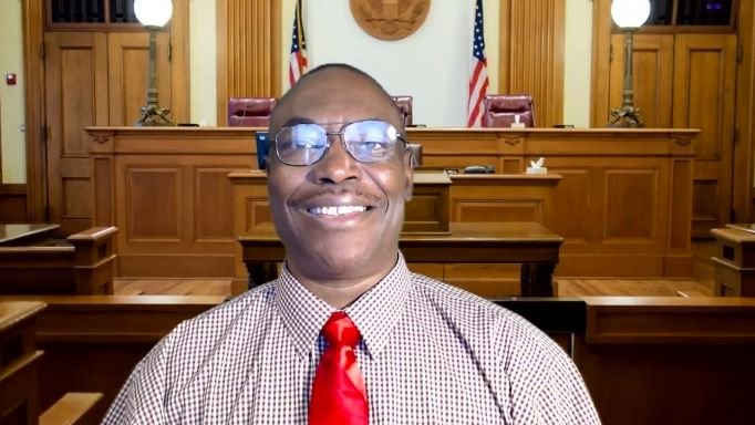 A man in a courtroom with a red tie.
