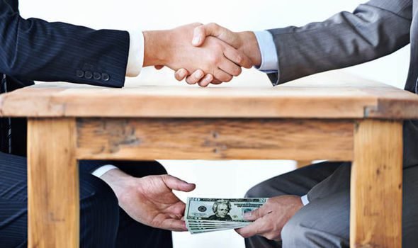 Two men shaking hands over a table with money.