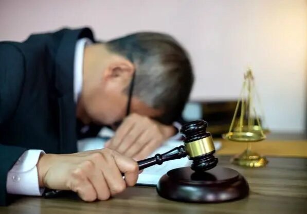A man with his head down holding a gavel A man with his head down holding a gavel