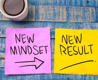 A cup of coffee and two sticky notes with new mindset and new results.