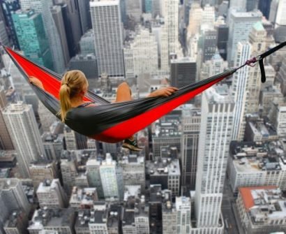 A woman is hanging in the air on a hammock.